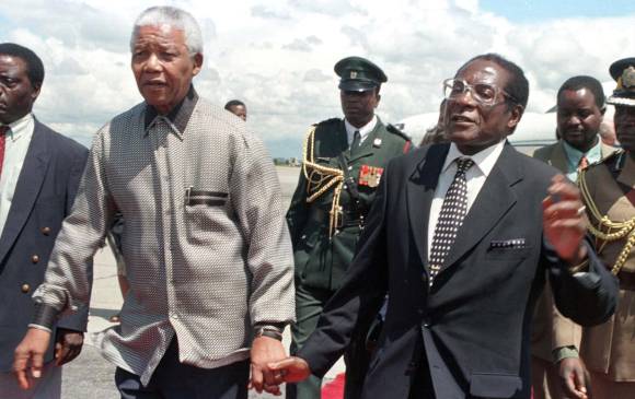 Nelson Mandela camina junto a Robert Mugabe en 1998 durante una visita de Mandela a Harare, capital de Zimbabue. FOTO Reuters