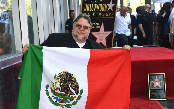Guillermo del Toro extendió la bandera mexicana al momento de recibir su estrella. FOTO AFP
