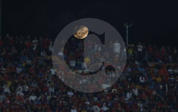 En una noche fría y lluviosa, la luna hizo su aparición en medio de un marco azul y rojo.