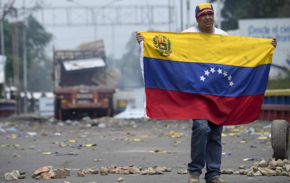 Un manifestante sostiene una bandera venezolana en el puente internacional Francisco de Paula Santander en Urena, Venezuela, frontera con Colombia- Foto: AFP