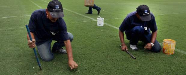 Un lunar entre tanta belleza | Róbinson Sáenz | Gabriel Durango y Mario Ruiz, expertos en el mantenimiento de canchas y contratados por la empresa Equiver, le quitaban ayer la maleza al césped del Atanasio. El viernes tuvieron mucho trabajo.