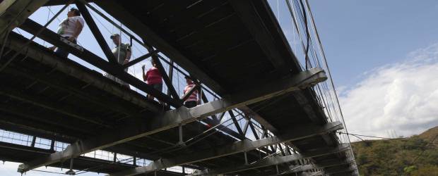 Bajo riesgo, peatones cruzan Puente de Occidente | Jaime Pérez | De acuerdo con los comerciantes de la zona, son más de 200 las personas que diariamente atraviesan el Puente de Occidente para evitar los altos costos que les implica dar la vuelta por la vía a Sopetrán que, según ellos, se encuentra en pésimo estado. Los vendedores reclaman soluciones definitivas.