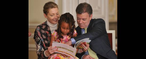 La discriminación en Colombia ya se castiga | César Carrión, Sig | La primera dama de la Nación, María Clemencia Rodríguez, junto al presidente Juan Manuel Santos disfrutan con una niña afrodescendiente de la lectura de un libro sobre la historia de la Casa de Nariño, durante el acto de sanción de la Ley Antidiscriminación.