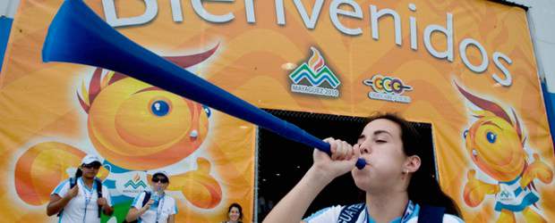 Suenan vuvuzelas centroamericanas | Cortesía, Www. Mayagüez-2010.com | La atleta Sabrina Magauran, de la selección de balonmano de Guatemala, toca su vuvuzela en la Zona Internacional de Mayagüez-2010. Ayer llegaba el grueso de las delegaciones de los 31 países que estarán en competencia. El ausente es Cuba, campeón de hace cuatro años en Cartagena.
