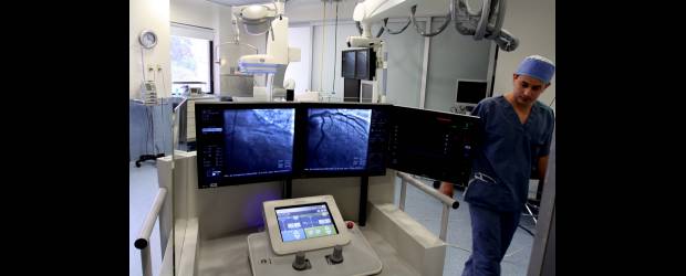 La misión de este robot es tocar el corazón | Manuel Saldarriaga | Desde esta cabina protegida con plomo para evitar la radiación, el cardiólogo tiene el control sobre el brazo robótico del Corpath 200. Una de las pantallas encuadra la lesión mientras la otra registra los avances de los elementos que se deslizan hasta el corazón: stent, globo endovascular, guía, medio de contraste.