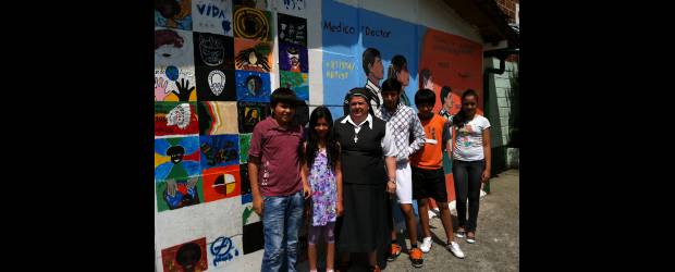 En Fe y Alegría educan a toda la familia | Camila Mesa Aristizábal | El mural Desearte Paz del Colombo Americano, ubicado en la Institución Educativa Fe y Alegría Popular 1, fue creado por artistas de diversos países a principios del año. La madre María Eugenia Echavarría desfila orgullosa con alumnos creadores de la exposición fotográfica de la estación Popular del metrocable.