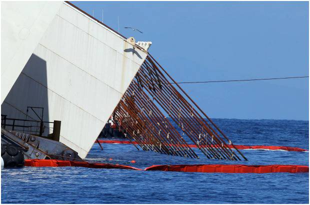 FOTOS AP - La rotaci&#243;n del barco, de 112.000 toneladas y 290,2 metros de eslora, se realiza con un minucioso proceso con gatos hidr&#225;ulicos que tensan los cables de acero unidos a la parte superior de unos cajones y plataformas instalados, mientras otros cables conectados a 13 torretas levantadas a estribor dieron equilibrio al buque.