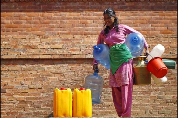AP - Una mujer nepalí espera para llenar sus recipientes con agua cerca de Patan, en Nepal.