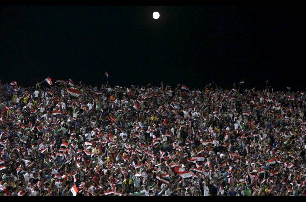 AP - Esta imagen es en Bagdad, Irak. La Luna asoma por encima de los aficionados al fútbol que animan a su equipo durante un partido amistoso en el estadio Al-Shaab en Bagdad, donde Irak ganó 2-1 sobre Siria.