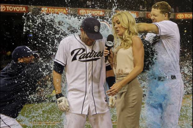 AP - El jugador de los padres de San Diego Chris Denorfia recibe el ba&#241;o de la victoria de Nick Hundley, a la derecha, y Ren&#233; Rivera mientras era entrevistado por Kelly Crull.