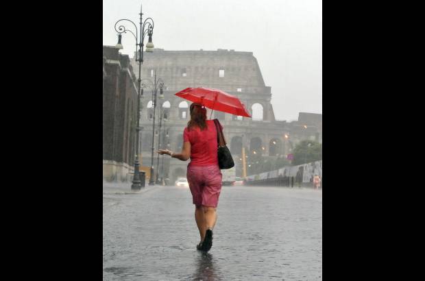 AP - Una mujer camina hacia el coliseo romano en un d&#237;a particular de lluvia en el verano de Roma.