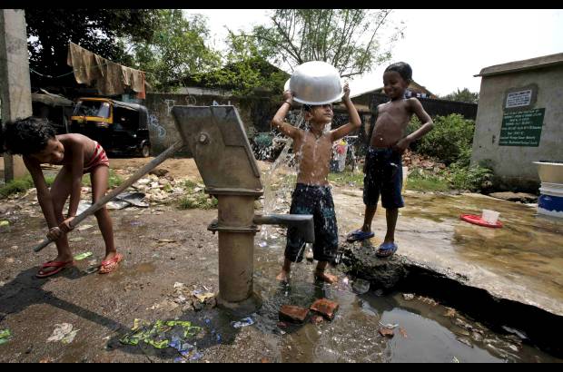 AP - Muchachos de Bhubaneswar, India, se bañan con agua de una bomba de mano.