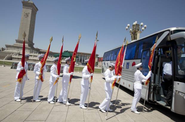 AP - 29 de mayo de 2014. Un grupo de J&#243;venes Pioneros, estudiantes con uniformes blancos y portando banderas rojas, suben a un autob&#250;s despu&#233;s de realizar vigilancia ceremonial alrededor del Monumento a los H&#233;roes del Pueblo en La plaza de Tiananmen.