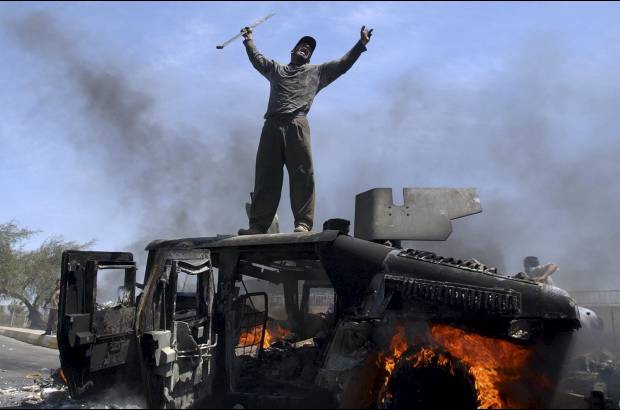 AP - Un hombre iraqu&#237; celebra sobre el veh&#237;culo quemado del ej&#233;rcito de Estados Unidos el 26 de abril de 2004.