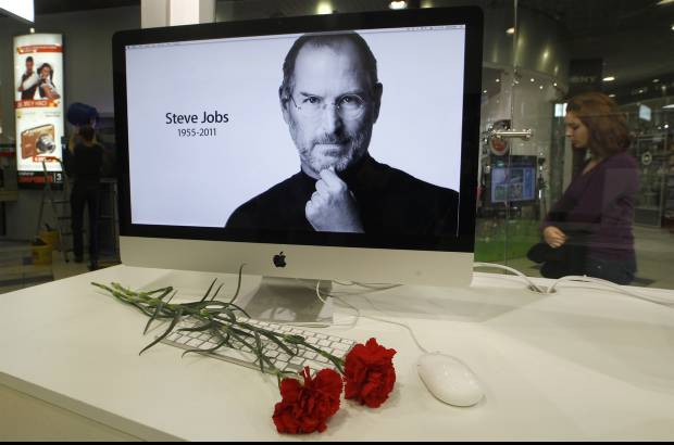 Reuters - Claveles rojos frente a una pantalla que muestra un foto de Steve Jobs, fue tan solo uno de los miles de tributos que recibió el cofundador de Apple, una de las muertes más sentidas de 2011.