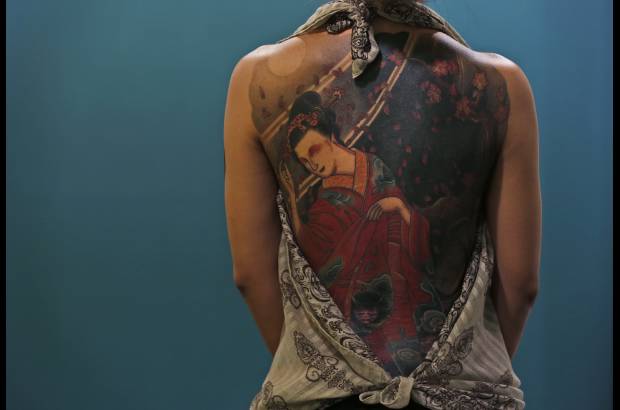 AP - Una mujer muestra su tatuaje durante la primera convenci&#243;n internacional de tatuaje en China.