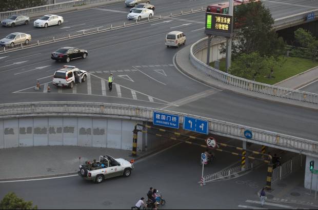 AP - 29 de mayo 2014. Un auto lleno de polic&#237;as cruza por el mismo puente en Beijing.