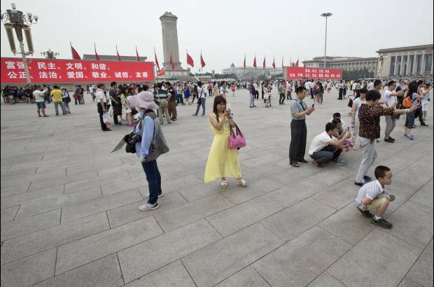 AP - 31 de mayo de 2014. Turistas chinos toman fotos con sus tel&#233;fonos inteligentes en la Plaza de Tiananmen. En los tableros electr&#243;nicos se leen palabras como prosperidad, democracia, civilizaci&#243;n, armon&#237;a, Justicia, Estado de derecho, Patriotismo, Dedicaci&#243;n profesional, integridad y amabilidad.