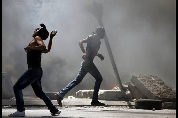 Reuters - Protestante palestino arroja una botella contra fuerzas israel&#237;es.