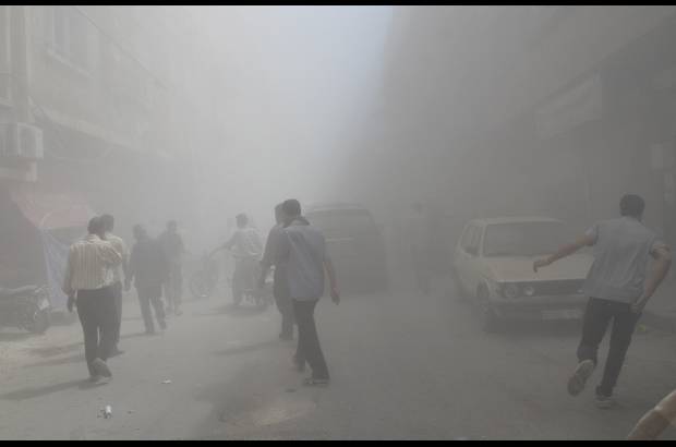 Reuters - Residentes del barrio Duma de Damasco caminan frente al humo despu&#233;s que activistas dijeran que era un ataque a&#233;reo de las fuerzas leales al presidente de Siria Bashar al-Assad