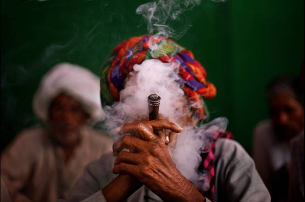 AP - Un aldeano indio fuma tabaco se une a otros manifestantes durante una manifestaci&#243;n exigiendo pensiones para los ciudadanos pobres de edad avanzada en Nueva Delhi, India.