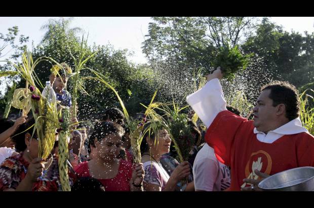 Reuters - Un sacerdote usa agua bendita para bendecir a los cat&#243;licos durante una misa antes de la procesi&#243;n de Domingo de Ramos a las afueras de la Catedral Metropolitana de Asunci&#243;n, Paraguay.