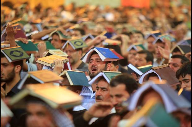 Reuters - Musulmanes chi&#237;tas usan una copia del Cor&#225;n en la cabeza durante una ceremonia para conmemorar el aniversario de la muerte del Imam Ali en su santuario en la ciudad santa de Najaf, a unos 160 kil&#243;metros al sur de Bagdad, Irak.