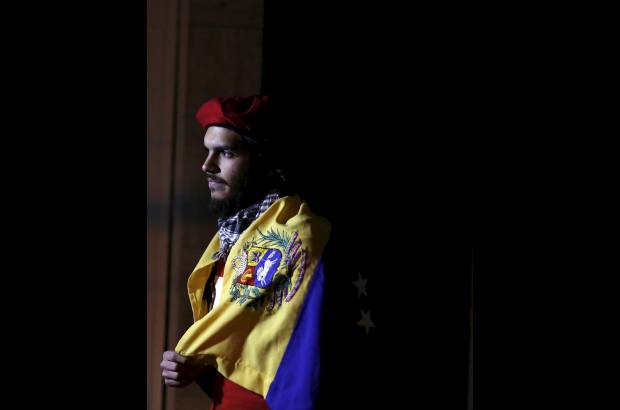 Reuters - Un partidario del presidente de Venezuela, Hugo Ch&#225;vez en M&#233;xico aguard&#243; en las afueras de la embajada de Venezuela en la Ciudad de M&#233;xico envuelto en una bandera venezolana.