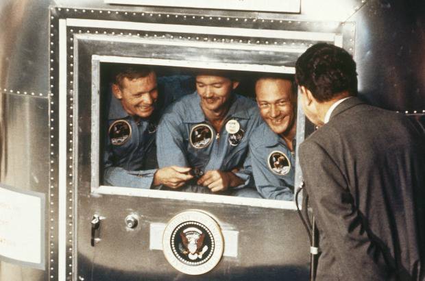AP - NASA - 24 de julio de 1969. El presidente Richard Nixon, a la derecha, saluda a los astronautas del Apolo 11 en la furgoneta de cuarentena, a bordo del USS Hornet, después del amerizaje y recuperación.
