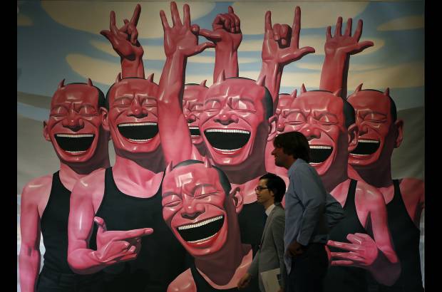 AP - Dos hombres caminan cerca a la obra del artista chino Yue Minjun llamada Entre el hombre y el animal durante el avance para la prensa de la subasta del artista en Hong Kong.