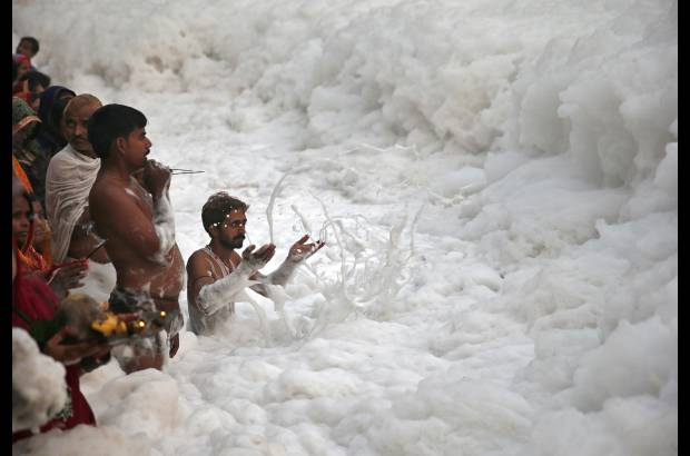 Reuters - Un devoto hind&#250; empuja la espuma para hacer espacio para otros devotos que buscan a adorar al dios Sol Surya en las aguas contaminadas del r&#237;o Yamuna.