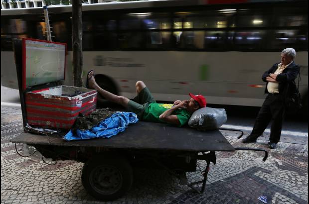 AP - En una acera del centro de Río de Janeiro, Elias Vieira, de 40 años, observa el partido de fútbol amistoso entre Brasil y Panamá, en un televisor de pantalla plana instalado en su carreta de trabajo.