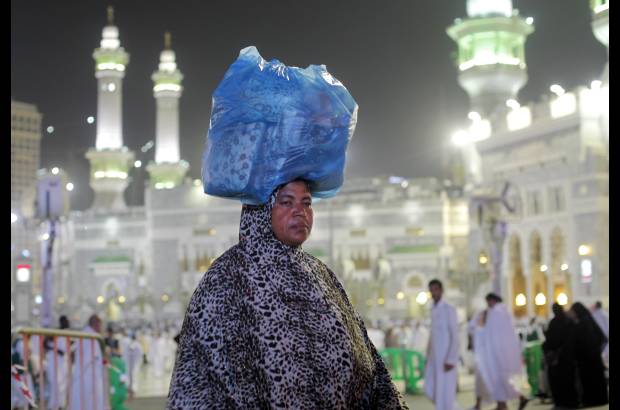 AP - Una peregrina musulm&#225;n lleva su equipaje frente a la Gran Mezquita de la ciudad santa de La Meca, Arabia.