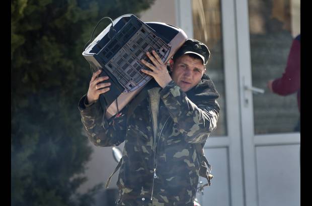 AP - Este aviador ucraniano lleva un televisor con &#233;l. El hombre deja la base a&#233;rea Belbek, Crimea.