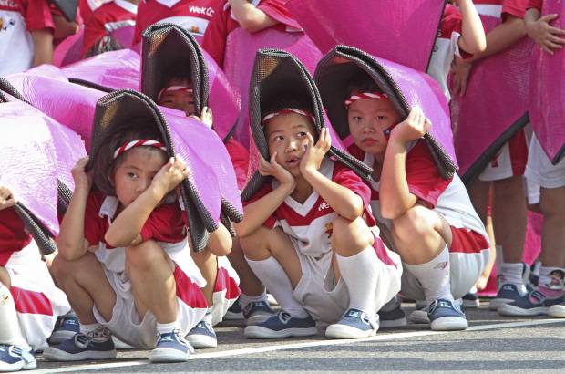 AP - Ni&#241;os taiwaneses cubren su cabeza para evitar el sol durante un ensayo para las celebraciones del D&#237;a Nacional en frente de la Oficina Presidencial en Taipei, Taiw&#225;n.