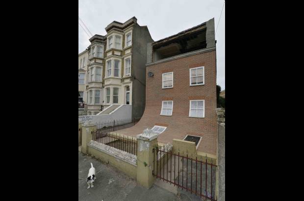 RE - Un perro permanece al lado de una pieza de arte realizada en la zona residencial en Margate, Inglaterra. La escultura fue creada por el artista Alex Chinneck y estar&#225; expuesta por un a&#241;o.