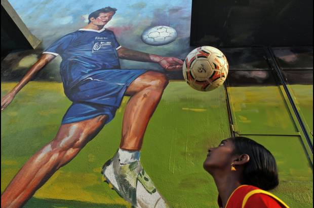 AP - En India, una niña cabecea un balón frente a un mural del excapitán de la selección de ese país, Baichung Bhutia, en un parque infantil en Chennai, India.
