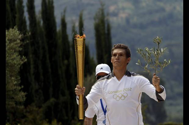 Foto Reuters - Spyridon Gianniotis, campe&#243;n de Grecia en nataci&#243;n, porta la Antorcha ol&#237;mpica y una rama de olivo durante el relevo en la antigua Olimpia en Grecia.