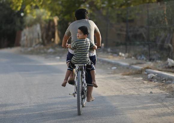 Reuters - Un joven palestino maneja su bicicleta con su hermano atr&#225;s en una calle al norte de Gaza.
