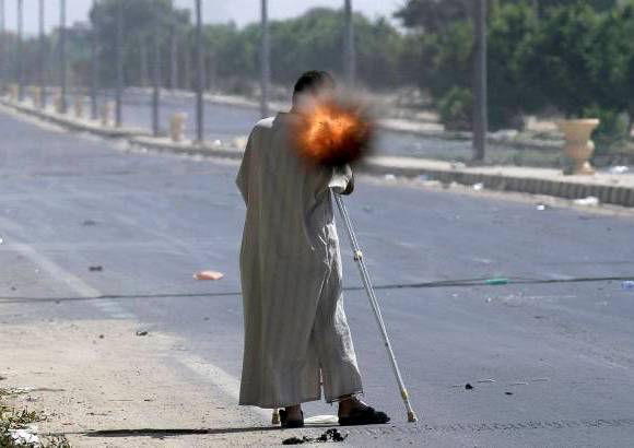 Reuters - Un rebelde con muletas disparando una granada propulsada por cohete mientras combatía en la ciudad de Sirte, Libia.