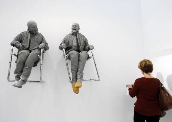 Reuters - Un visitante observa la obra "2 sentados en el muro con grandes sillas" del artista Juan Muñoz durante la Feria Internacional de Arte Contemporaneo en Paris.