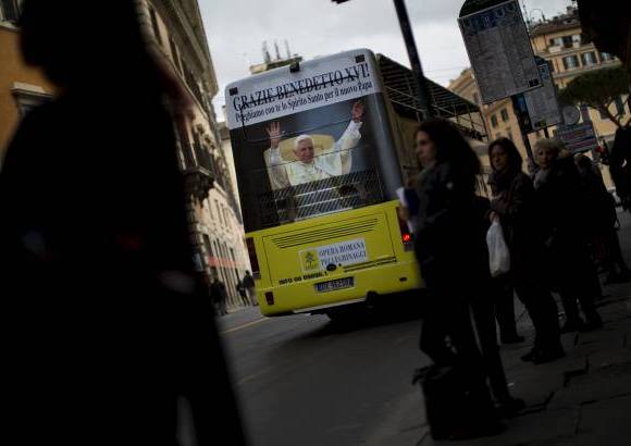 AP - Una imagen del Papa Benedicto XVI se ve en un autob&#250;s tur&#237;stico en Roma, horas antes del comienzo de la elecci&#243;n del nuevo papa.