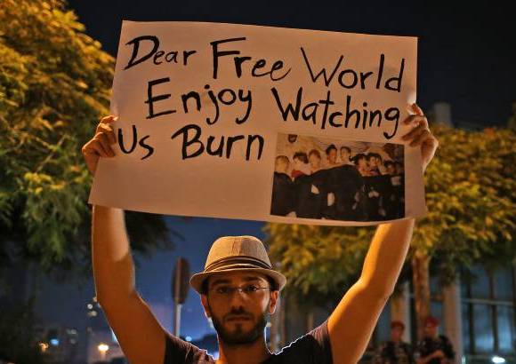 AP - Un hombre sirio que vive en Beirut, sostiene un cartel durante una vigilia por el supuesto ataque de armas qu&#237;micas en los suburbios de Damasco. El hombre est&#225; al frente a la sede de Naciones Unidas en Beirut, L&#237;bano.