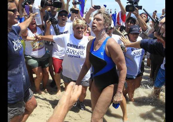 REUTERS - Con los labios hinchados, apariencia aturdida y quemada por el sol, la estadounidense Diana Nyad se convirti&#243; el lunes en la primera persona en cruzar las traicioneras aguas entre Cuba y Cayo Hueso sin una jaula que la proteja de los tiburones.