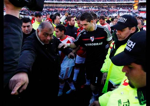 Reuters - Los futbolistas riverplatenses, rodeados de policías, debieron esperar en el campo de juego varios minutos tras la finalización del partido que igualaron con el Belgrano (1-1), a causa de que numerosos aficionados intentaban saltar al campo para agredirlos.