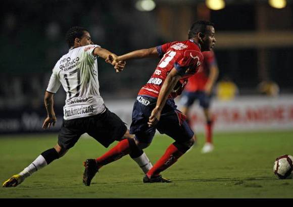 AP - El &#250;nico gol lleg&#243; a los 22 minutos tras un centro del veterano astro Roberto Carlos, que el defensor de Corinthians William desvi&#243; primero, para que luego Juan Valencia, del Medell&#237;n, metiera la pelota en su propio arco al intentar despejar.