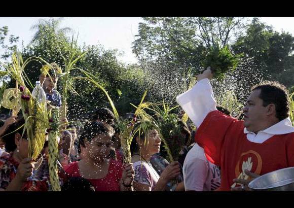 Reuters - Un sacerdote usa agua bendita para bendecir a los cat&#243;licos durante una misa antes de la procesi&#243;n de Domingo de Ramos a las afueras de la Catedral Metropolitana de Asunci&#243;n, Paraguay.