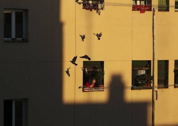 RE - Un hombre mira por la ventana despu&#233;s de alimentar a las palomas en pleno centro de Madrid