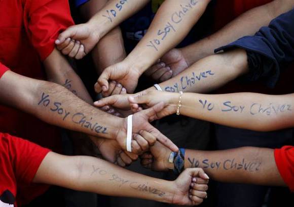reuters - Maduro cerró un acto de "juramentación simbólica" celebrado en los alrededores del palacio presidencial de Miraflores, en donde se congregaron los seguidores del mandatario usando camisas rojas con el lema #YoSoyChávez y bandas presidenciales de papel tricolor.