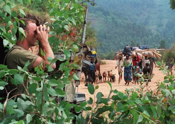 AFP - En esta foto de archivo del 12 de julio de 1994, un soldado francés que se escondía detrás de un árbol, miraba a través de binoculares cómo miles de personas que huían de los sangrientos combates entre el ejército de Ruanda y el Frente de Liberación Nacional se dirigían al campo de refugiados de Kivumu, al oeste del país.